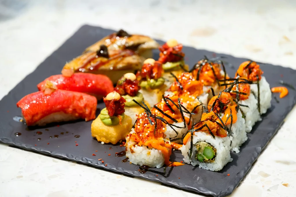 Platter of sushi, nigiri, and various Japanese appetizers on a dark slate.