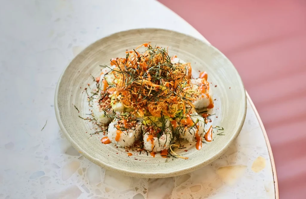 Deconstructed sushi dish with crispy topping, nori, and reddish sauce.