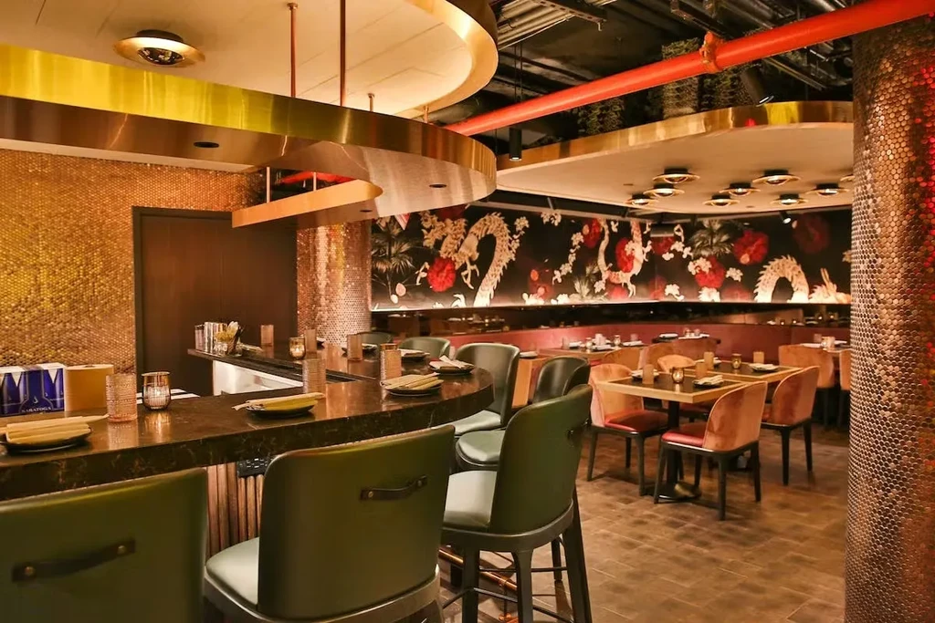 Luxurious restaurant interior with dragon wallpaper, gold ceiling, and dark bar.