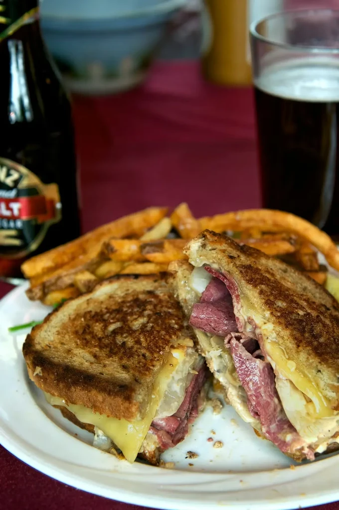 Grilled sandwich with meat, cheese, and fries, served with drinks.