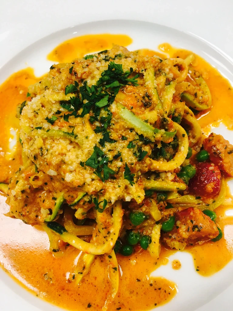 Vegetable pasta with creamy orange sauce, peas, tomatoes, and cheese.
