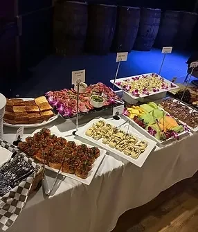 A dark, moody buffet table featuring charcuterie, appetizers, and fruit.