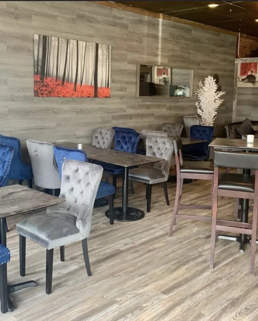 Empty modern restaurant with blue velvet seating, wood, and forest art.