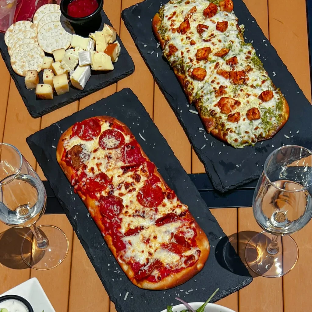 Dining spread with charcuterie, two flatbread pizzas, and water.