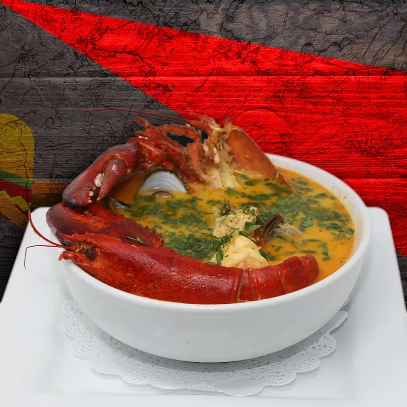 White bowl of yellow seafood soup, with a large red cooked lobster.