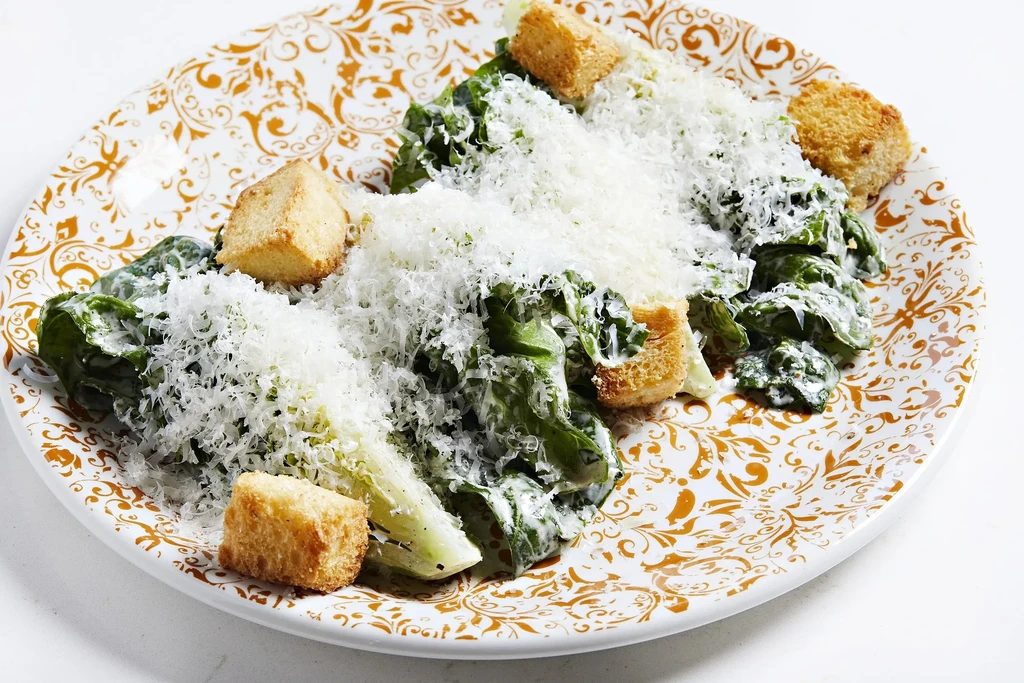 Creamy Caesar salad with Parmesan and croutons on a scrollwork plate.