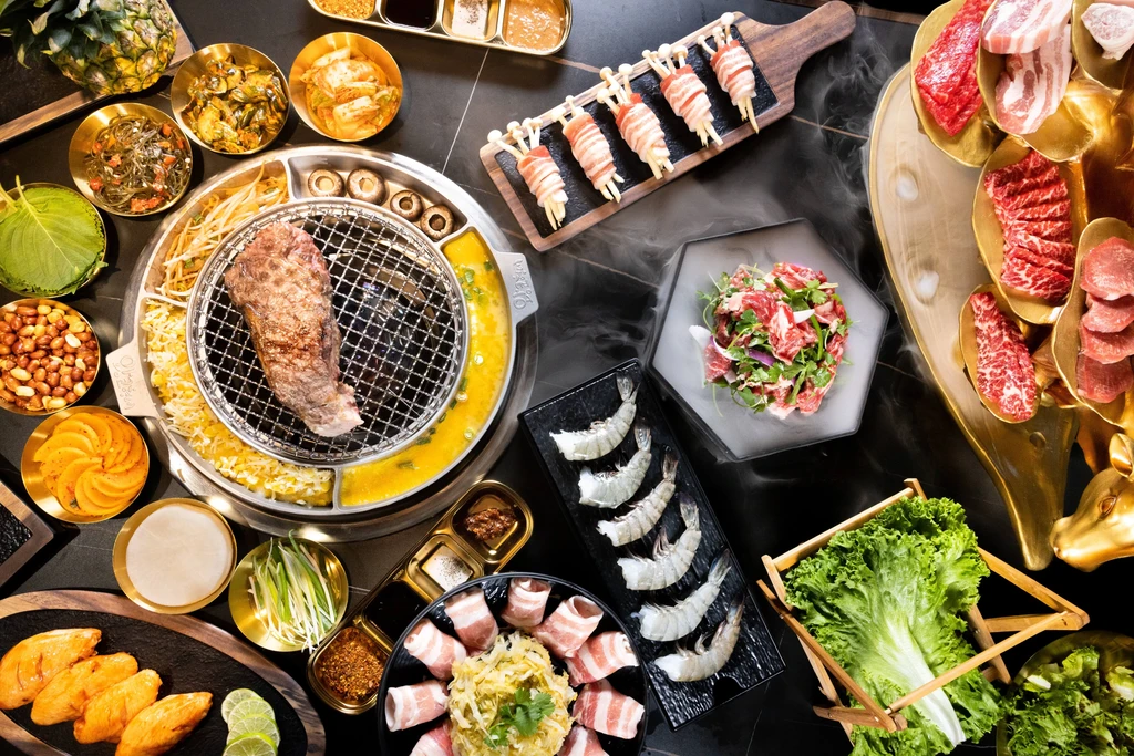 Lavish Korean barbecue spread with sizzling grill, raw meats, and banchan.