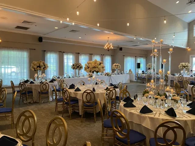 Formal banquet hall with gold chairs, navy accents, and floral centerpieces.