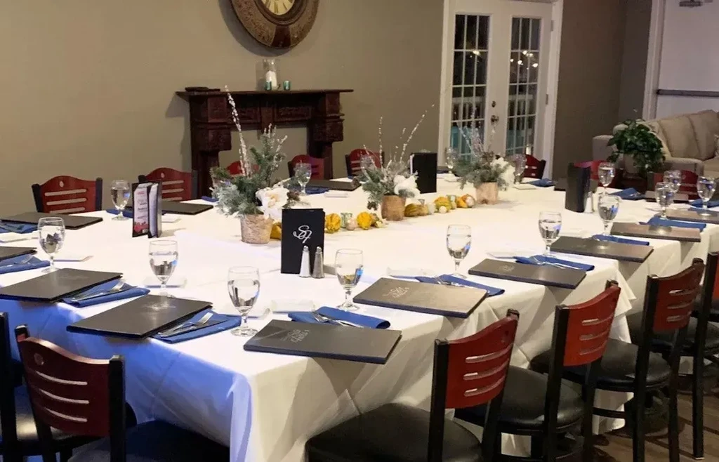 Meticulously set dining table with festive evergreen and gourd decorations.