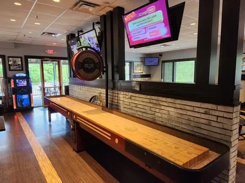 Restaurant entertainment area with shuffleboard, digital jukebox, and TVs.
