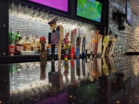 Reflective bar counter displaying beer taps and liquor bottles.