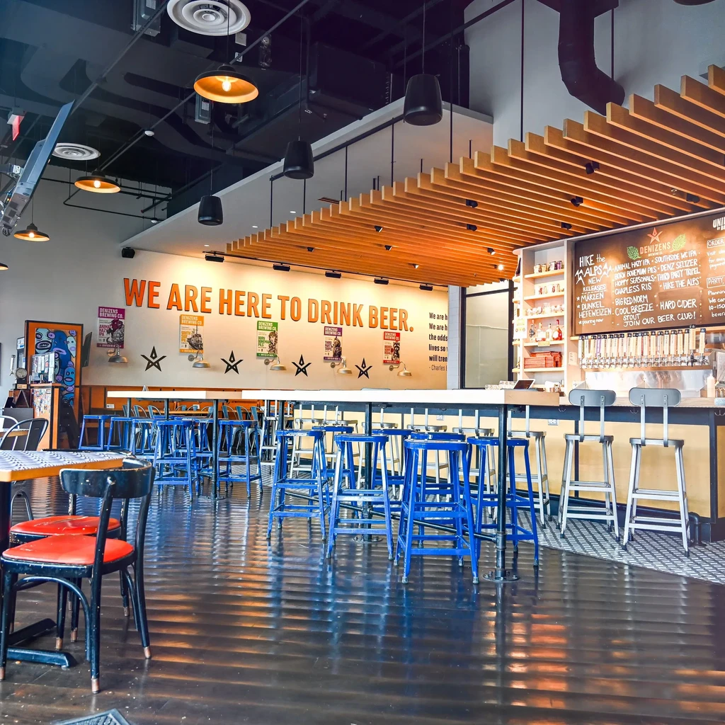 Empty Demizens Brewing Co. interior with "WE ARE HERE TO DRINK BEER" mural.