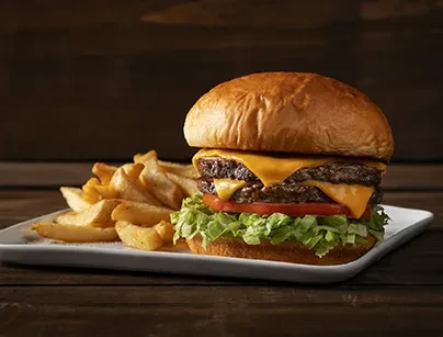 Double cheeseburger with melted cheese, lettuce, tomato, and thick-cut fries.