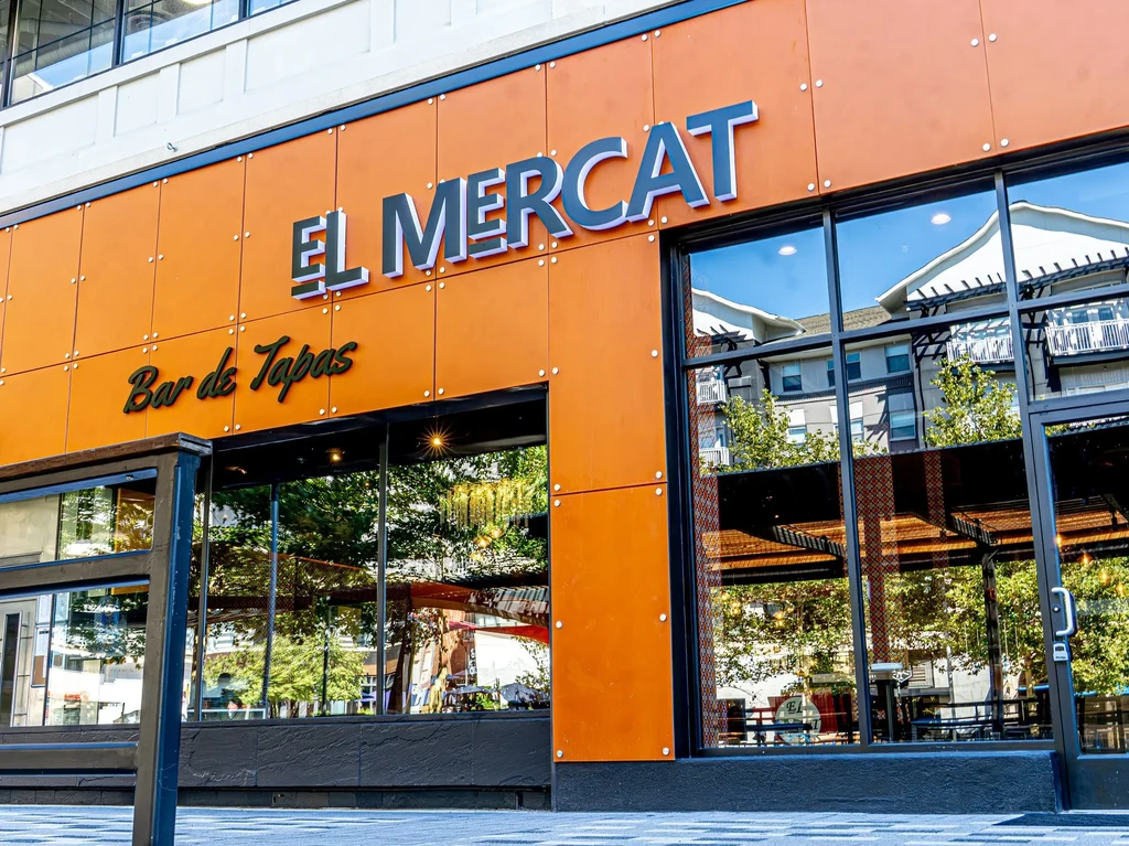 Modern orange restaurant facade, El Mercat Bar de Tapas, reflective windows.
