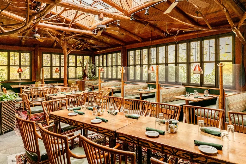Well-lit rustic restaurant interior with log ceiling, skylights, and green seating.