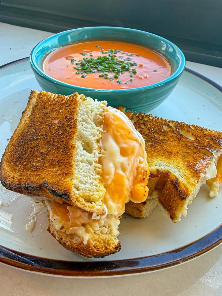 Gooey grilled cheese and vibrant tomato soup garnished with chives.