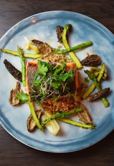 Plated salmon, asparagus, morel mushrooms, microgreens, and grains.