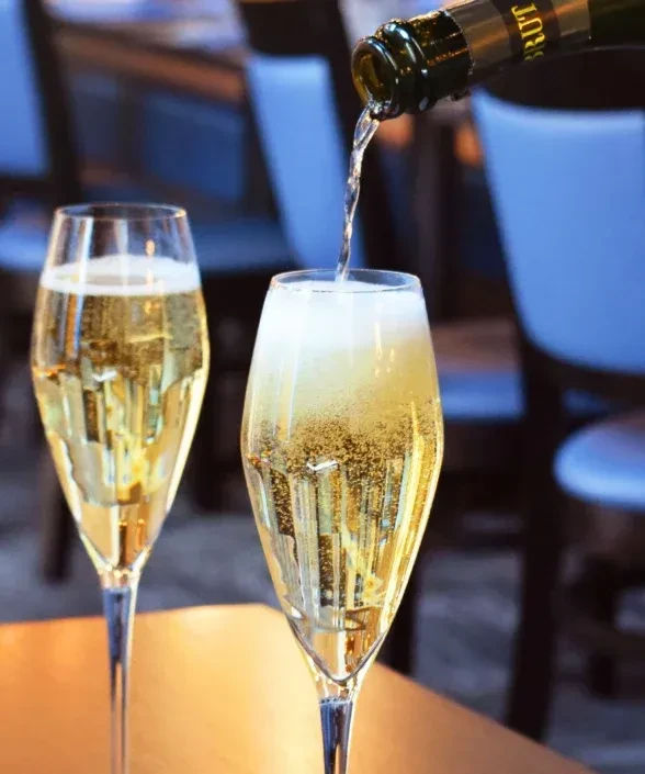 Golden Brut champagne pours into a flute, forming a foamy head.