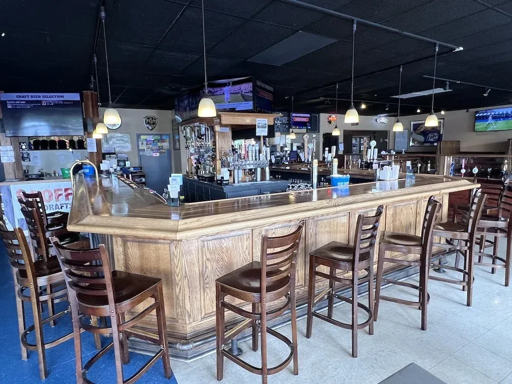 Empty U-shaped wooden bar, numerous beer taps, and sports on TVs.