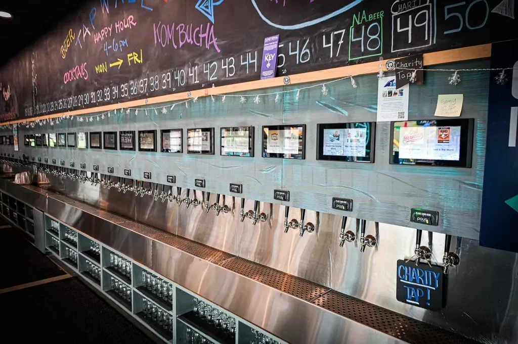 Extensive self-pour tap wall, digital screens, and a vibrant chalk menu.