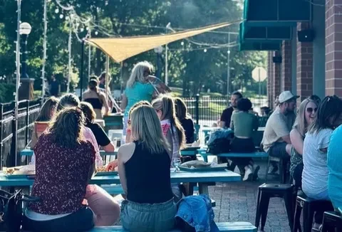 People socializing at a lively outdoor restaurant patio with string lights.