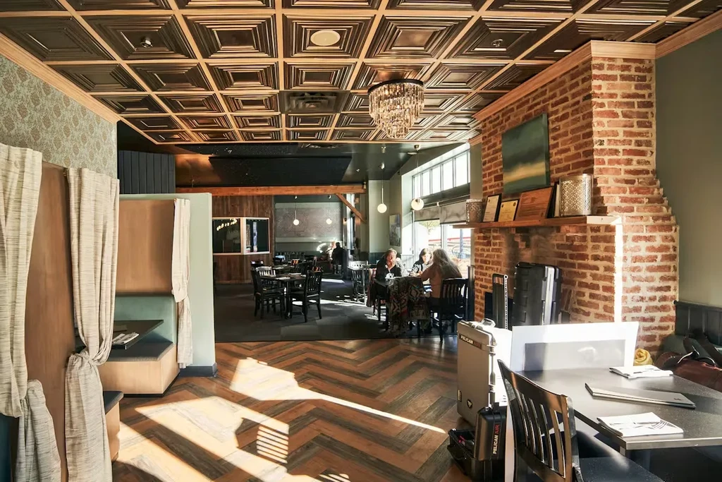 Modern rustic restaurant interior with natural light and patrons dining.