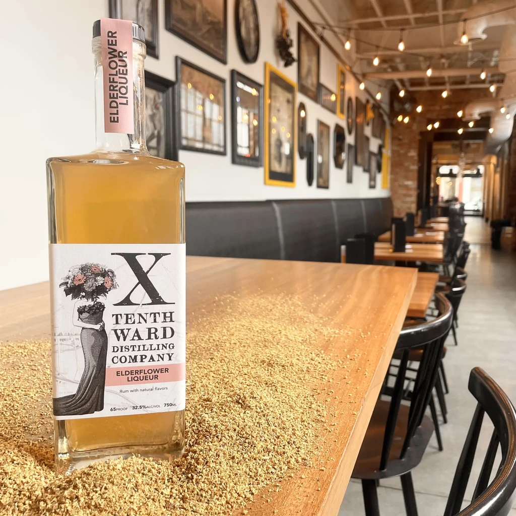 Bottle of Elderflower Liqueur on a table with dried flowers.