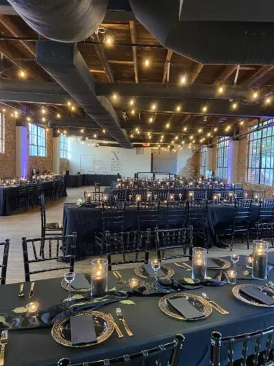 Elegant event hall, black and gold tables, industrial decor, 'TRUST THE HALL' sign.
