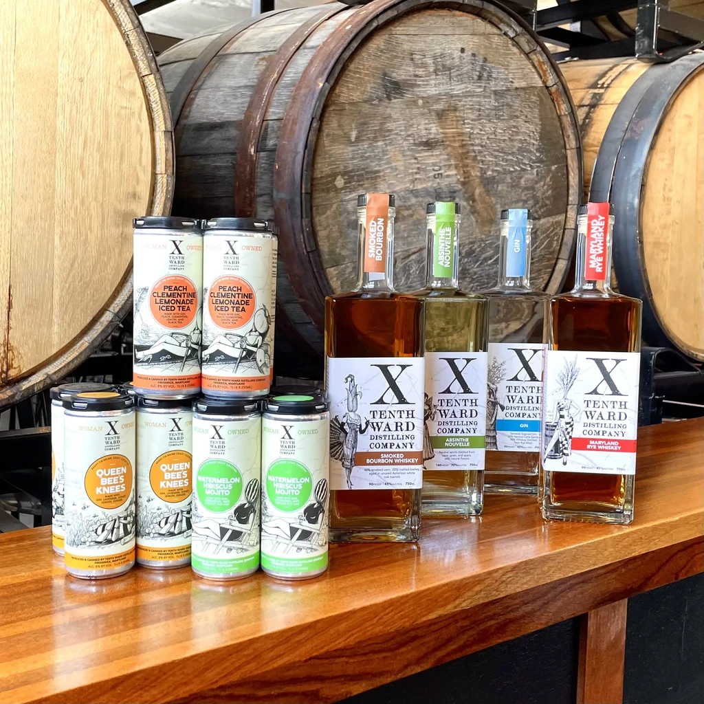 Ready-to-drink cocktails and spirits from Tenth Ward Company with distillery barrels.