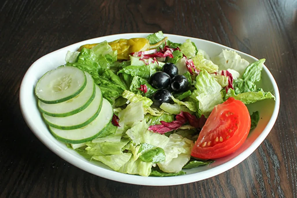 Mixed green salad with tomato, cucumber, black olives, pickled pepper.