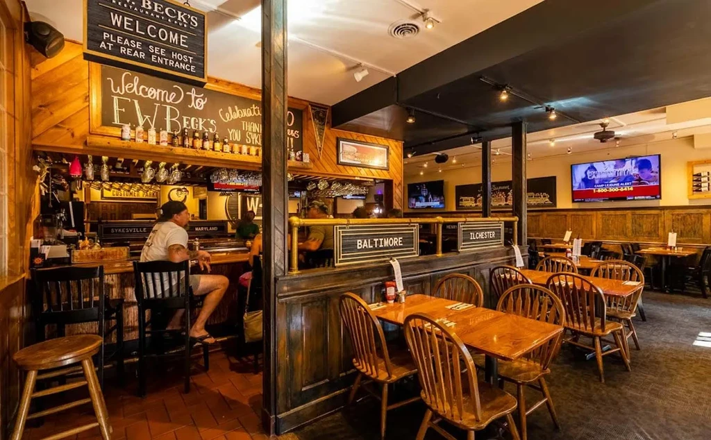 Interior of a rustic pub with a bar, dining room, and patrons.
