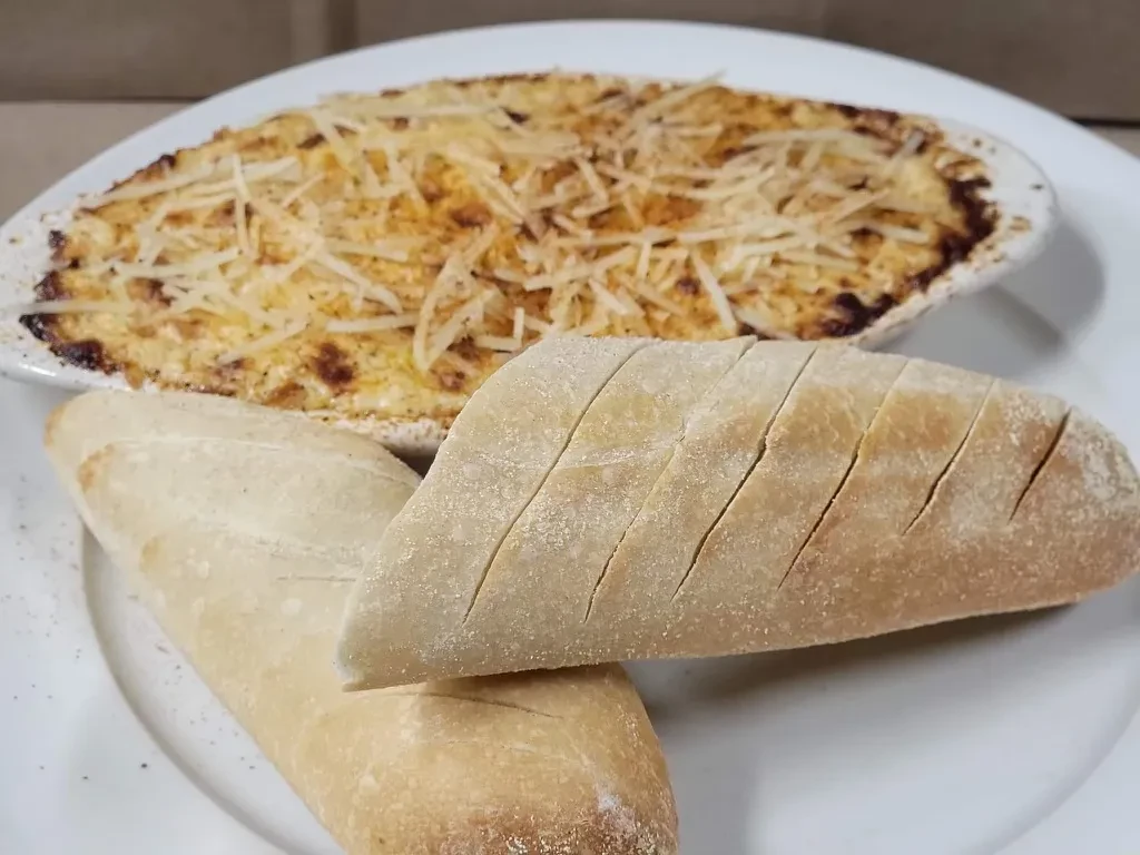 Golden-brown cheesy baked dip with caramelized crust and sliced bread.