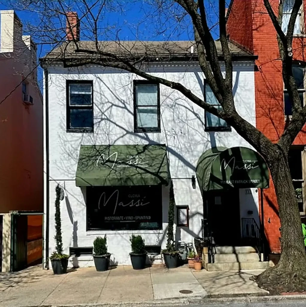 White brick Massi Italian restaurant exterior with dark green awnings.