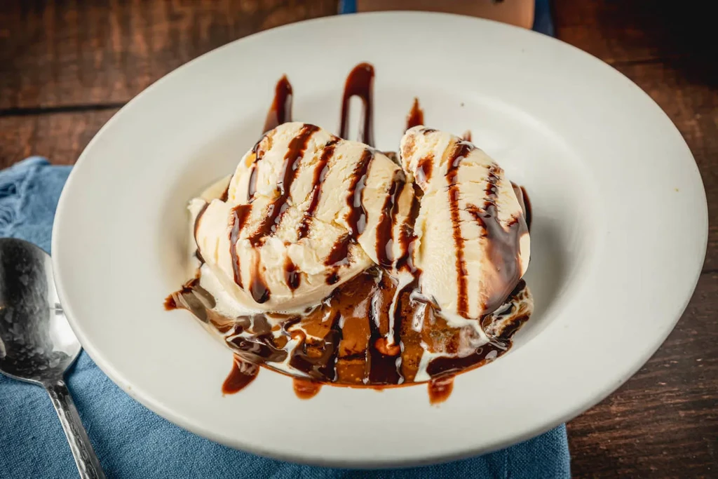 Vanilla ice cream with chocolate syrup over a warm brownie.