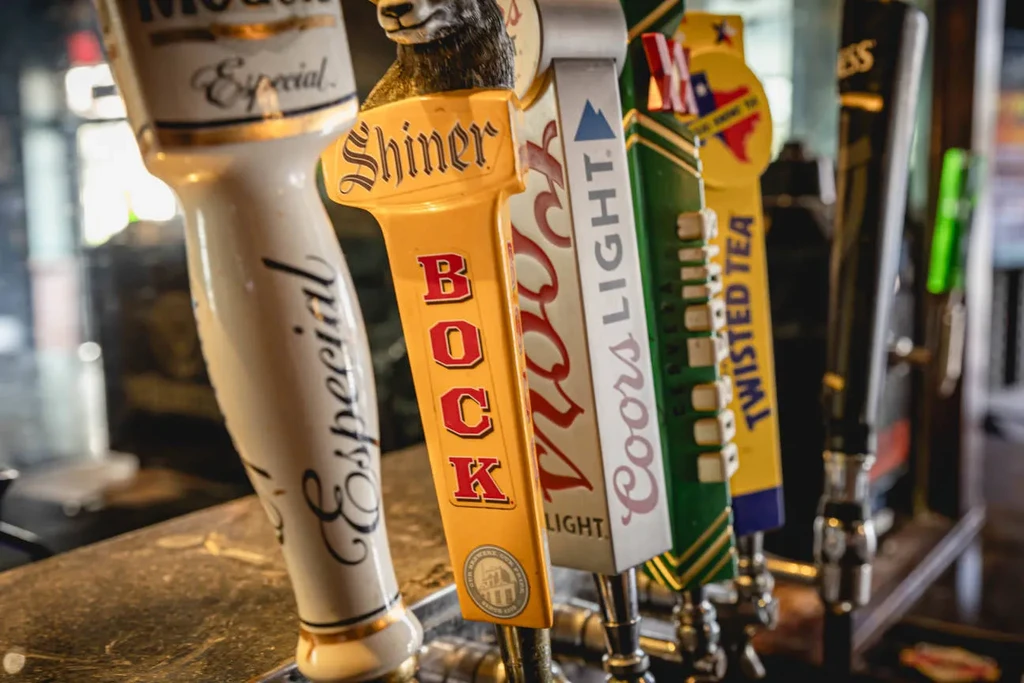Close-up of five beer tap handles lined up on a bar.