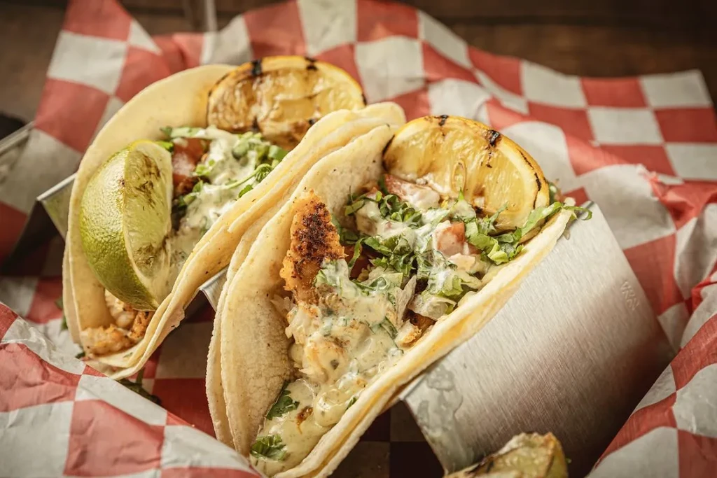 Two tacos filled with fried fish or chicken and vegetables.