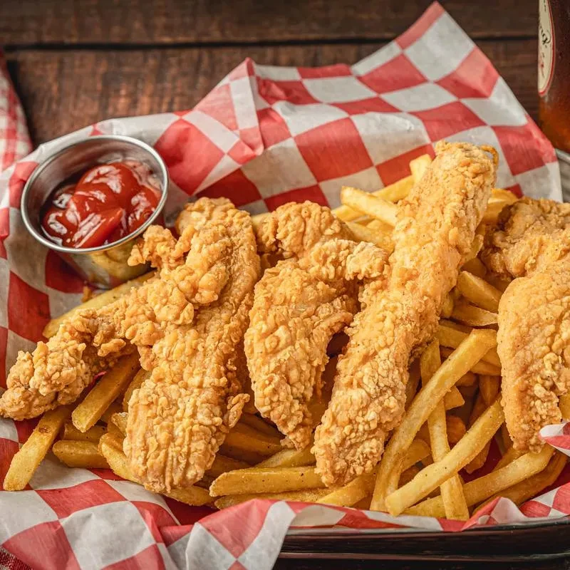Basket of crispy fried chicken tenders and french fries.