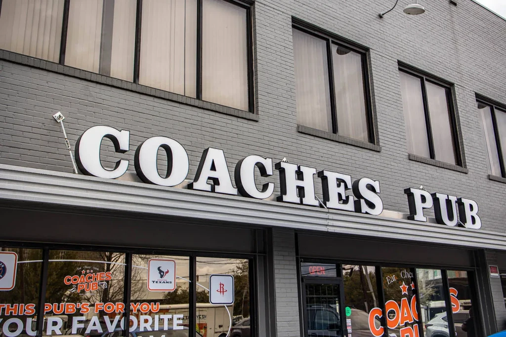 Exterior of Coaches Pub with large sign and reflective windows.