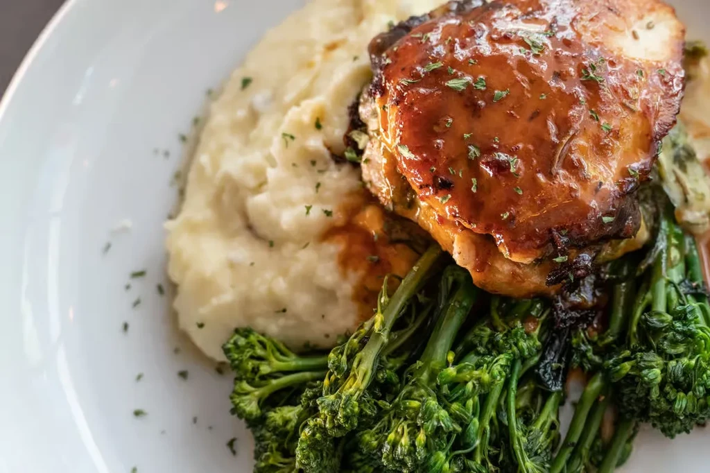 Glazed chicken/pork with mashed potatoes and green vegetables.