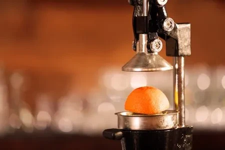 Close-up of a manual juicer with an orange half on its platform.