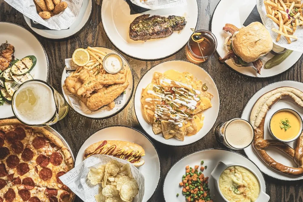 Overhead shot of a wooden table laden with diverse dishes and drinks.