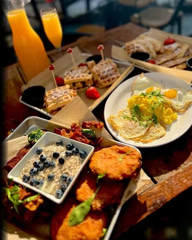 Breakfast spread: waffles, oatmeal, sweet potatoes, bacon, and eggs.