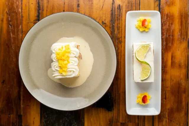 Two dessert servings, one with whipped cream, one with lime and strawberry.