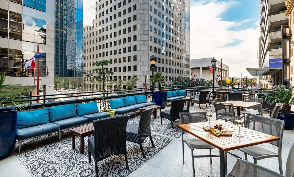 Outdoor restaurant patio with snacks, wine, and high-rise city views.