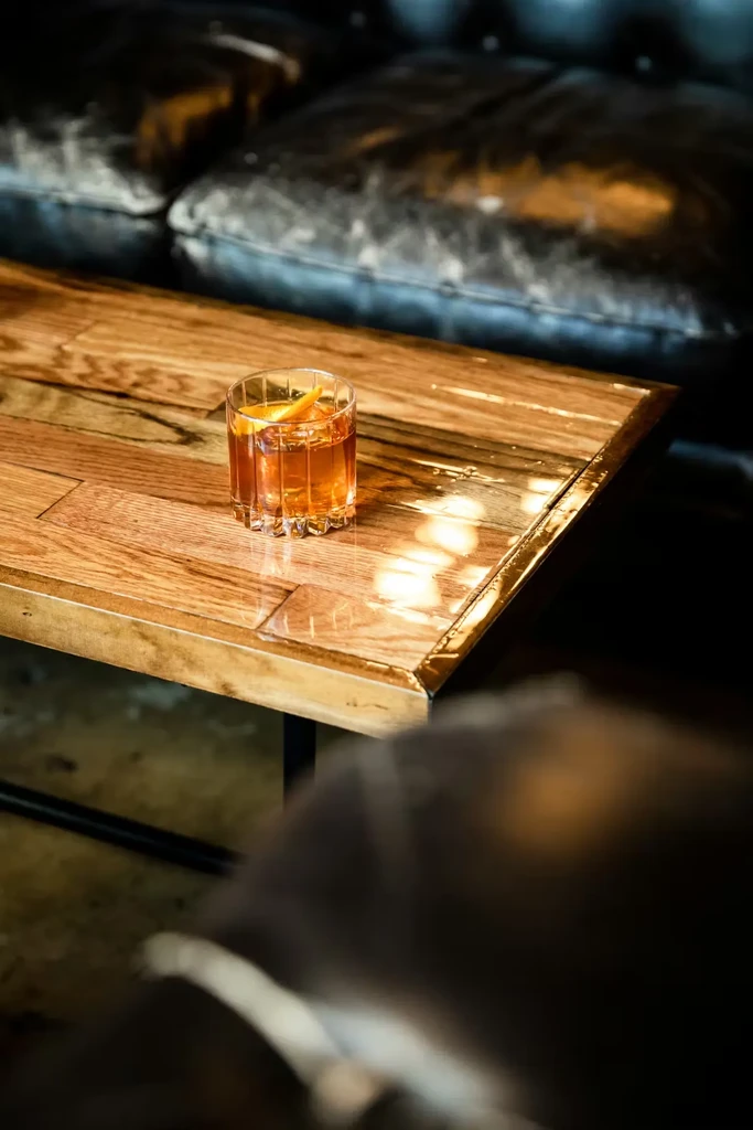 Amber drink in a ribbed glass with an orange peel.