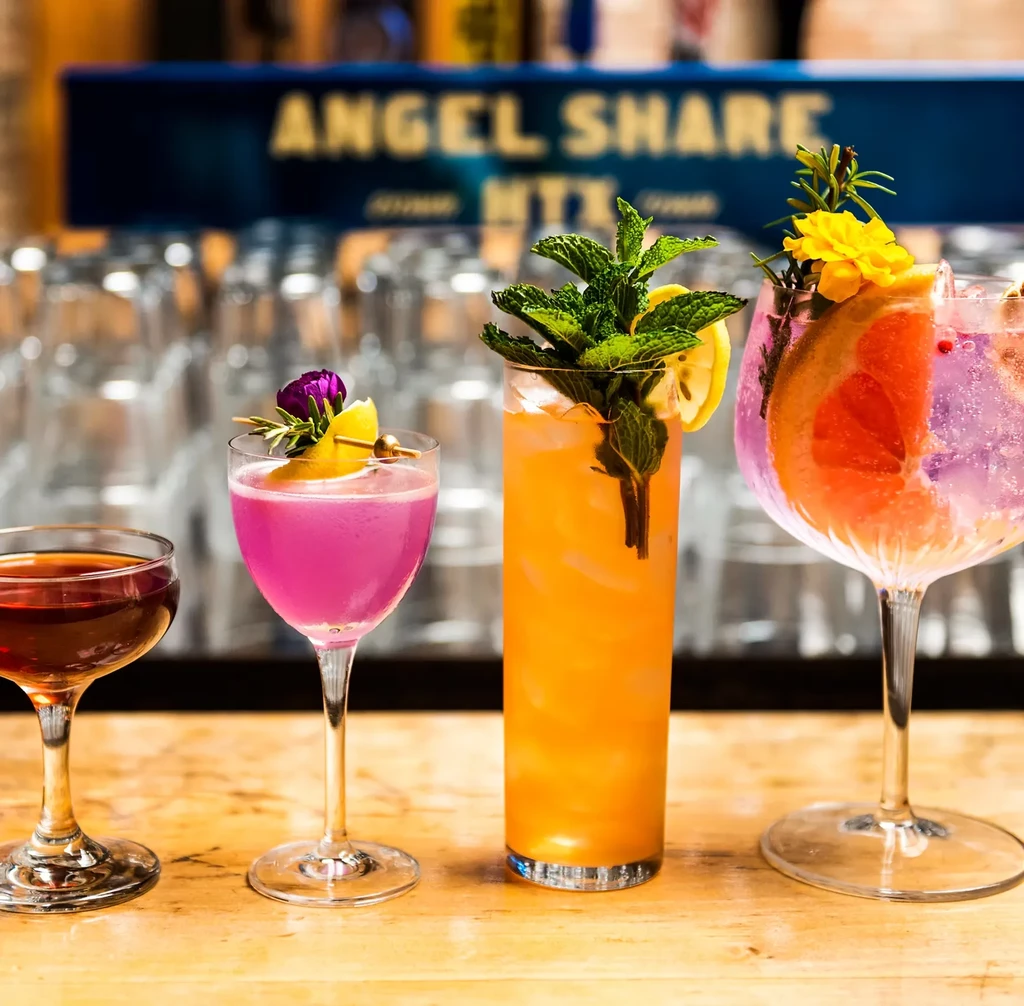 Four cocktails on a bar, with an "ANGEL SHARE" sign.