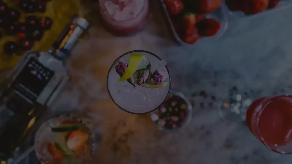 Overhead shot of drinks and ingredients on a dark surface.