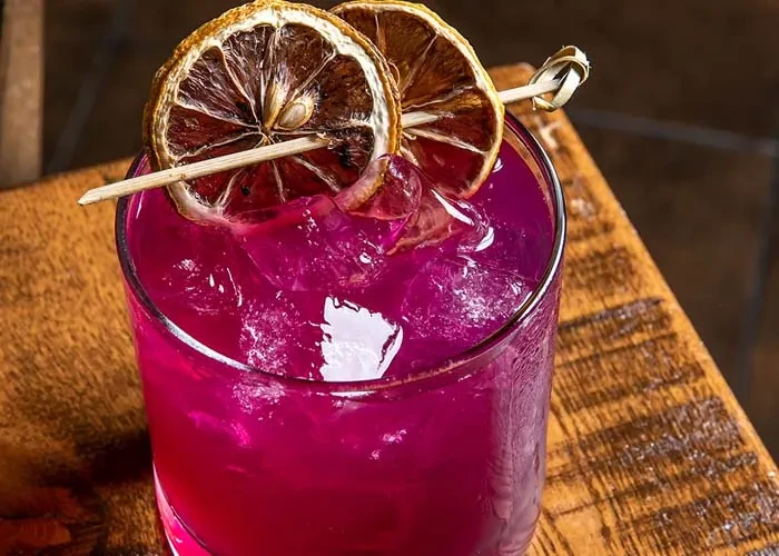 Fuchsia drink with ice and two dried citrus slices.
