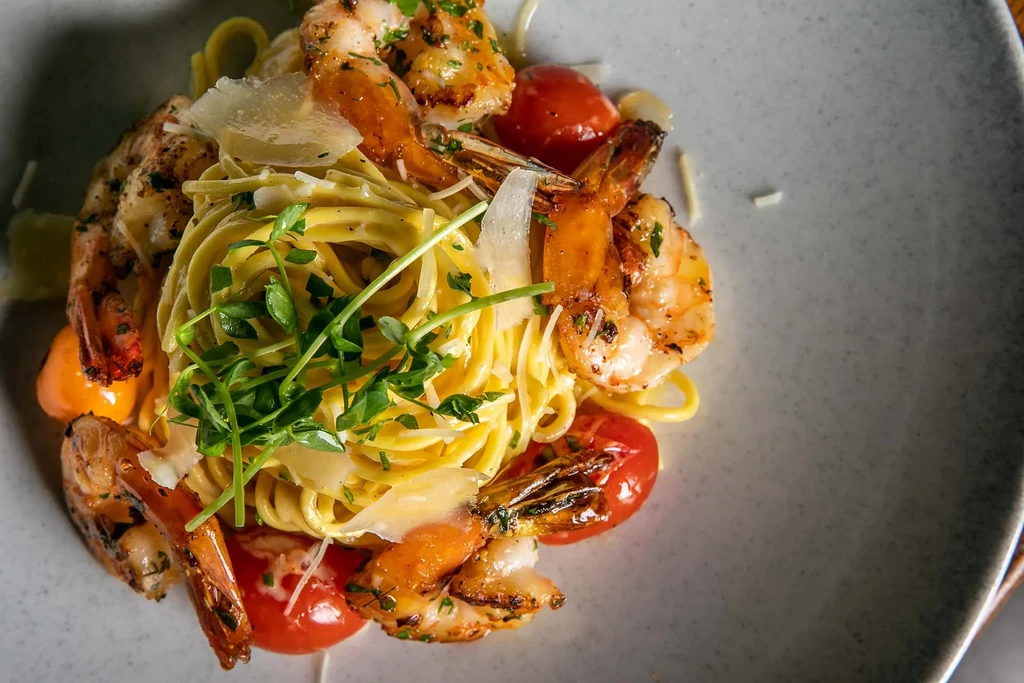Overhead shot of tagliatelle pasta with shrimp, tomatoes, and Parmesan.
