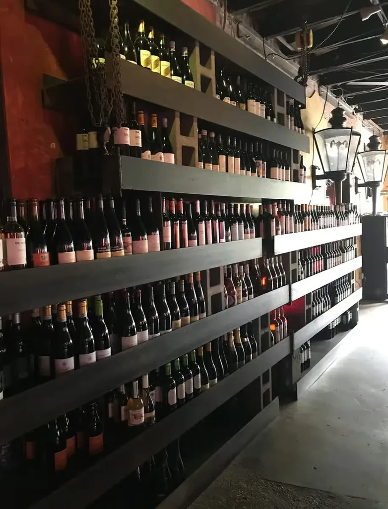 Wall shelves filled with wine bottles in a rustic restaurant setting.